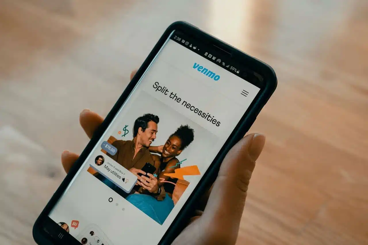 Smartphone displaying Venmo app screen with "Split the necessities" message, showing how to add money to Venmo and share expenses between friends.