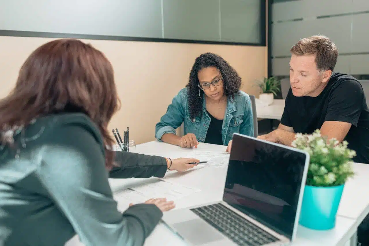 Business owners in a meeting with a CPA, signing Power of Attorney (POA) forms to authorize the CPA to request an IRS 147c letter, with laptop and documents visible on the table.