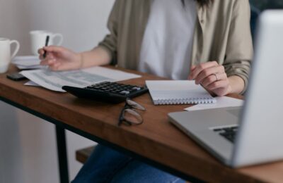 Person working on tax documents related to IRS Code 290, with calculator, notebook, and laptop on desk, illustrating the process of decoding and addressing tax issues.