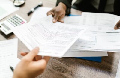 Hands reviewing financial transcripts on a wooden desk with calculator, potentially discussing IRS code 971 implications.