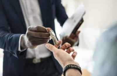 Close-up of hands exchanging keys, with one person in a business suit, suggesting a rental property transaction or management scenario related to rental property tax considerations.