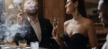 Elegant couple at upscale bar with champagne and cigar, illustrating luxury items subject to sin tax regulations in hospitality venues.