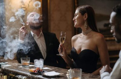 Elegant couple at upscale bar with champagne and cigar, illustrating luxury items subject to sin tax regulations in hospitality venues.