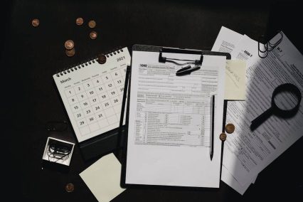 Escena de preparación de impuestos con el formulario 1040, calendario, monedas y documentos, relevante para diversos procesos fiscales, incluidos los relacionados con el Código 766 del IRS.