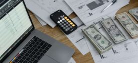 Desktop with laptop, calculator, financial documents, and cash, illustrating tax savings tips for small business owners engaged in financial planning and tax strategy.