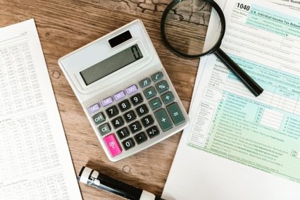 Tax Topic 151 preparation with IRS Form 1040, calculator, magnifying glass, and financial documents on wooden desk, illustrating the process of resolving IRS notices and calculating taxes.