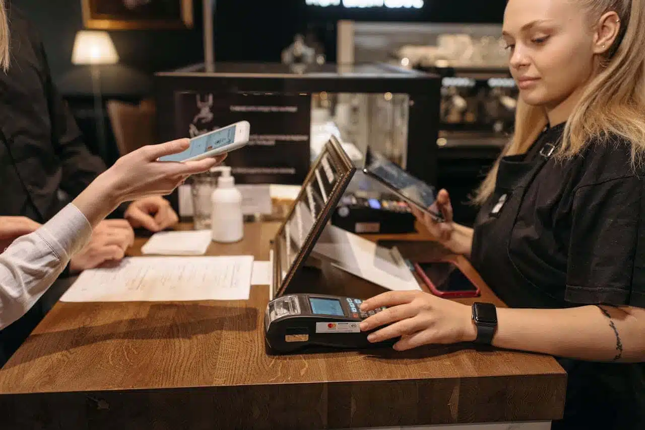 Venmo for teens payment at retail counter - customer demonstrating how a Venmo teen account works with digital payment terminal and smartphone